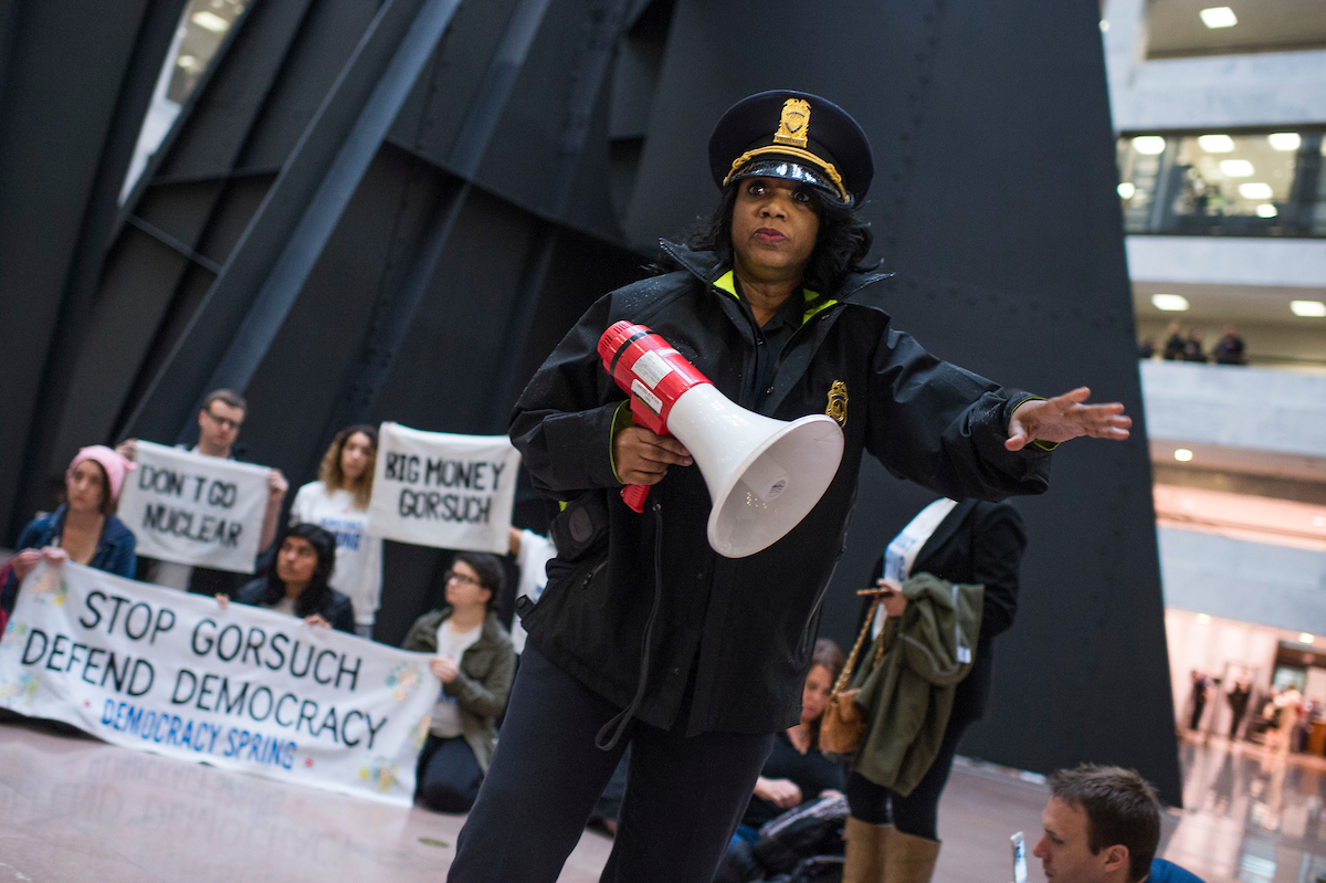 UNITED STATES - APRIL 6: A Capitol Police officer moves people away from a Democracy Spring protest in Hart Building where demonstrators urged the Senate not to use the nuclear option to confirm Supreme Court Justice nominee Neil Gorsuch, April 6, 2017. (Photo By Tom Williams/CQ Roll Call)