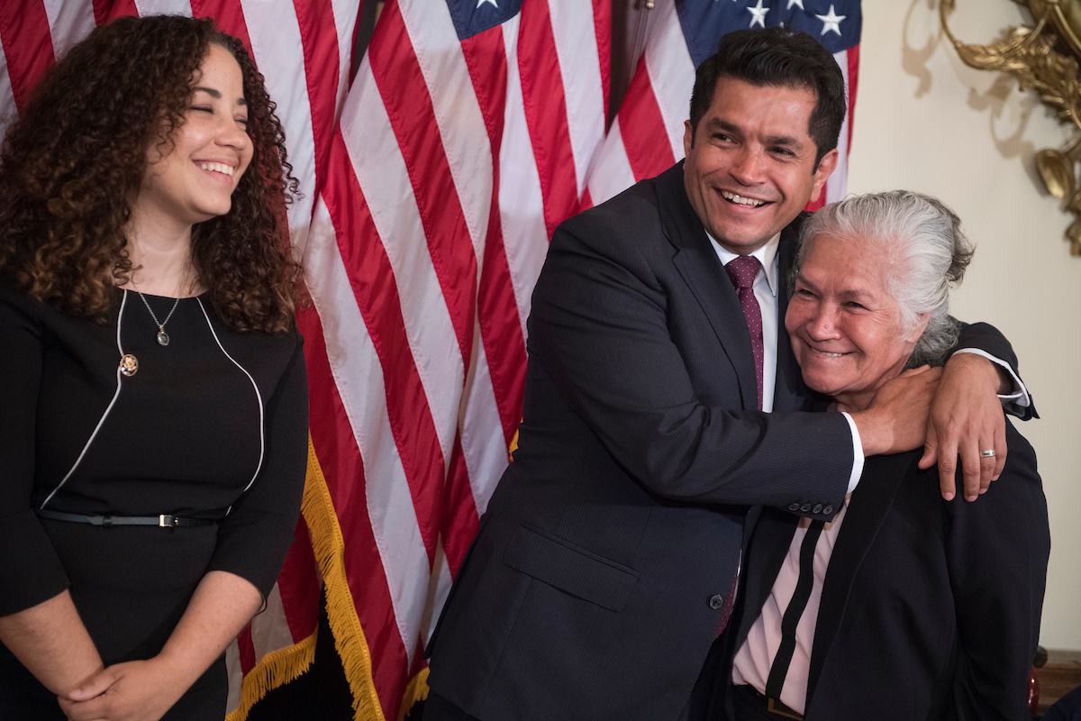 California Rep.-elect Jimmy Gomez hugs his mother, Socorro, as his wife, Mary Hodge, looks on, during his ceremonial House swearing-in Tuesday. (Tom Williams/CQ Roll Call)