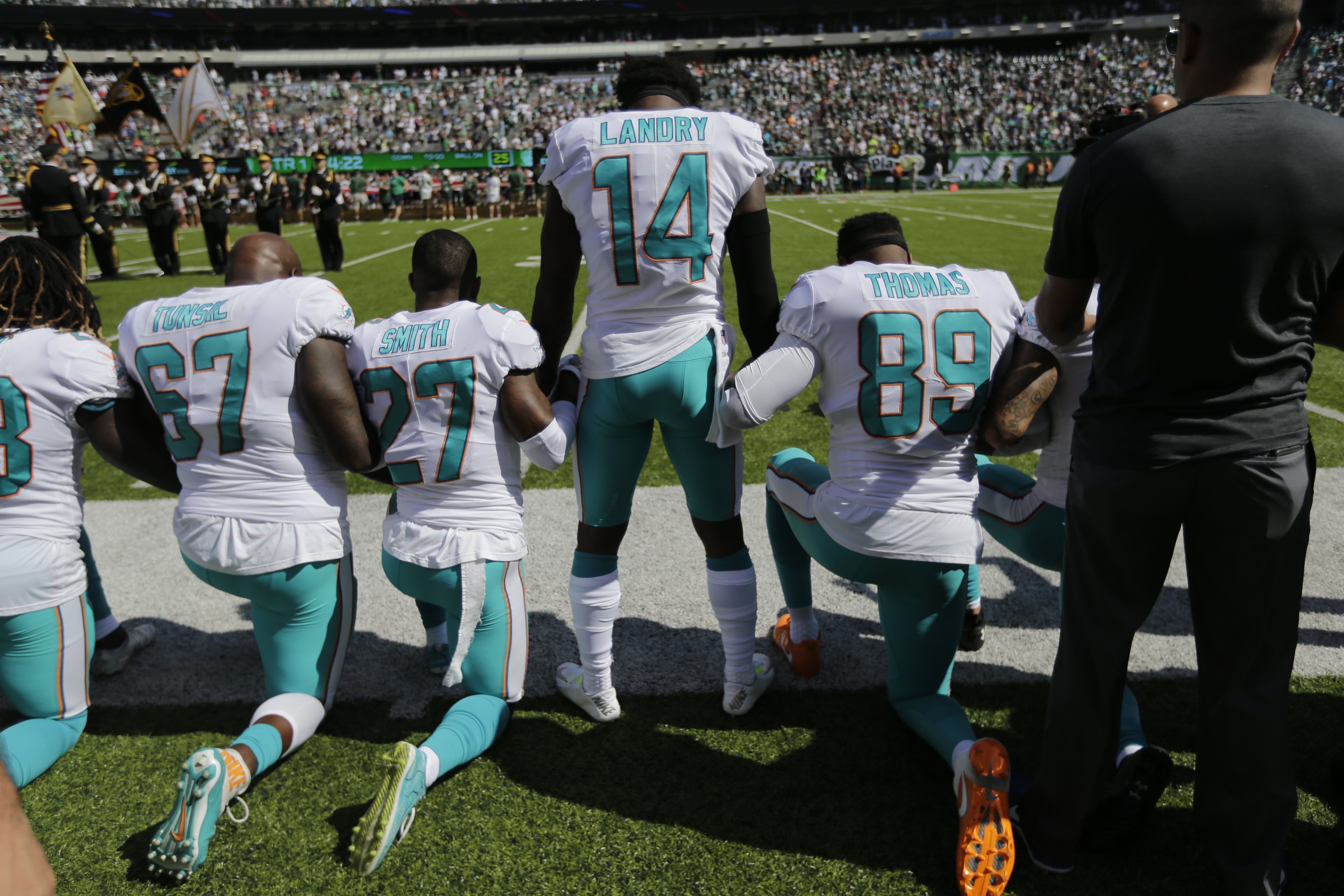 Miami Dolphins offensive tackle Laremy Tunsil (67), Maurice Smith (27), Jarvis Landry (14) lock hands with teammates during the playing of the national anthem before an NFL football game against the New York Jets on Sunday. (Seth Wenig/AP)