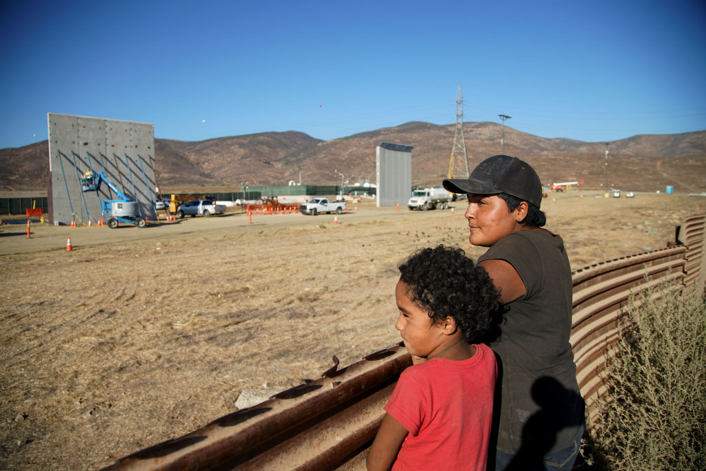 Aurelia Lopez and her daughter Antonia overlook construction of border wall prototypes on October 5, 2017, in Tijuana, Mexico. Prototypes of the border wall proposed by President Donald Trump have been built just north of the U.S.-Mexico border. (Sandy Huffaker/Getty Images file photo)