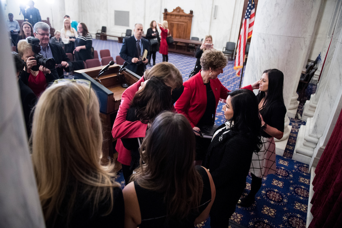 Sen. Dianne Feinstein, D-Calif., hugs Olympic gymnast Jamie Dantzscher as Rep. Susan W. Brooks, R-Ind., speaks with Olympic gymnast Dominique Moceanu, right, at the end of the press conference on legislation to prevent future abuse of young athletes. (Bill Clark/CQ Roll Call)