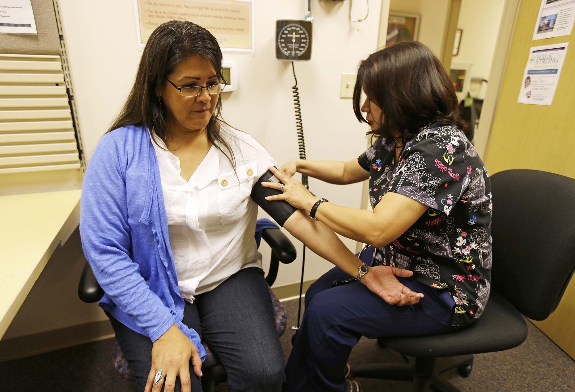 In this photo taken Thursday, April 11, 2013 Liz DeRouen, 49, left, gets her blood pressure checked by medical assistant Jacklyn Stra, right, at the Sonoma County Indian Health Project in Santa Rosa, Calif. When DeRouen needs any kind of health care services, from diabetes counseling to a dental cleaning, she checks into a government-funded clinic in Northern California's wine country that covers all her medical needs. Her care and the medical services for her children and grandchildren are paid for as part of the government's obligations to American Indian tribes dating back nearly a century. But under President Barack Obama's health care overhaul, DeRouen and tens of thousands of others who identify as Native American will face a new reality. They will have to buy their own health insurance policies or pay a $695 fine from the Internal Revenue Service unless they can prove they are "Indian enough" to claim one of the few exemptions allowed under the Affordable Care Act's mandate that all Americans carry insurance. (AP Photo/Eric Risberg)