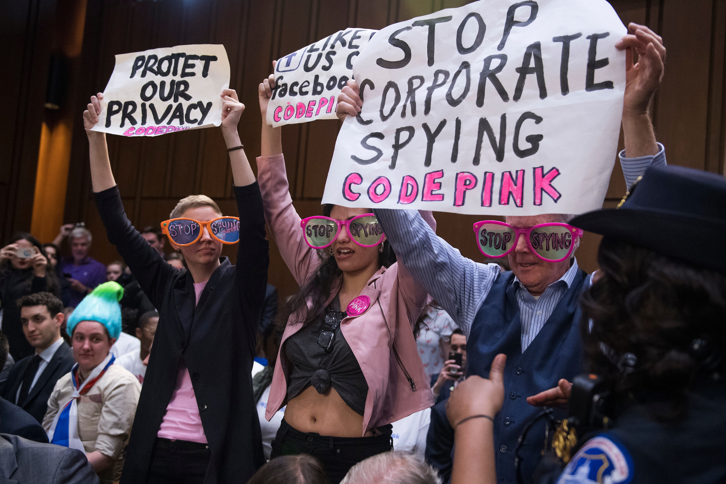 Protesters hold signs before Facebook CEO Mark Zuckerberg testified before a joint hearing of the Senate Judiciary and Commerce committees on the protection of user data in the Hart Building on Tuesday. ( Tom Williams/CQ Roll Call)