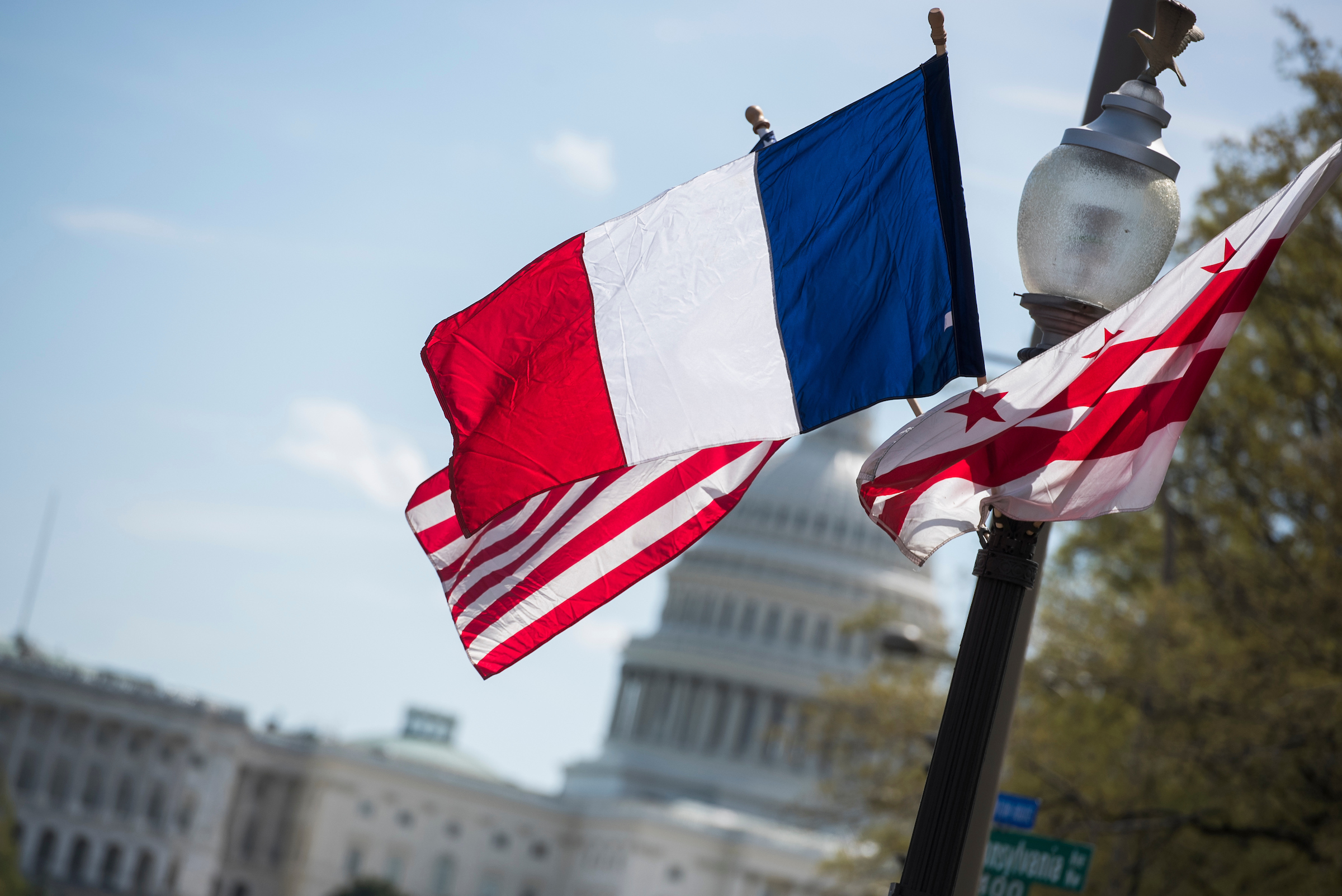 American, French and Washington, D.C., flags fly on Pennsylvania Avenue on Monday ahead of the official state visit of President Emmanuel Macron of France, who arrived later that day. (Tom Williams/CQ Roll Call)