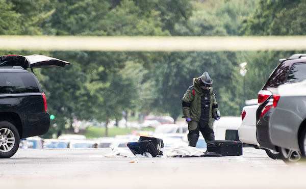 UNITED STATES - SEPTEMBER 12: An officer in a bomb suit sifts through luggage on Louisiana Ave. near the Capitol on Wednesday, Sept. 12, 2018. Capitol Police and other law enforcement were investigating an incident in which a suspect abandoned a suspicious vehicle on Capitol Hill.(Photo By Bill Clark/CQ Roll Call)