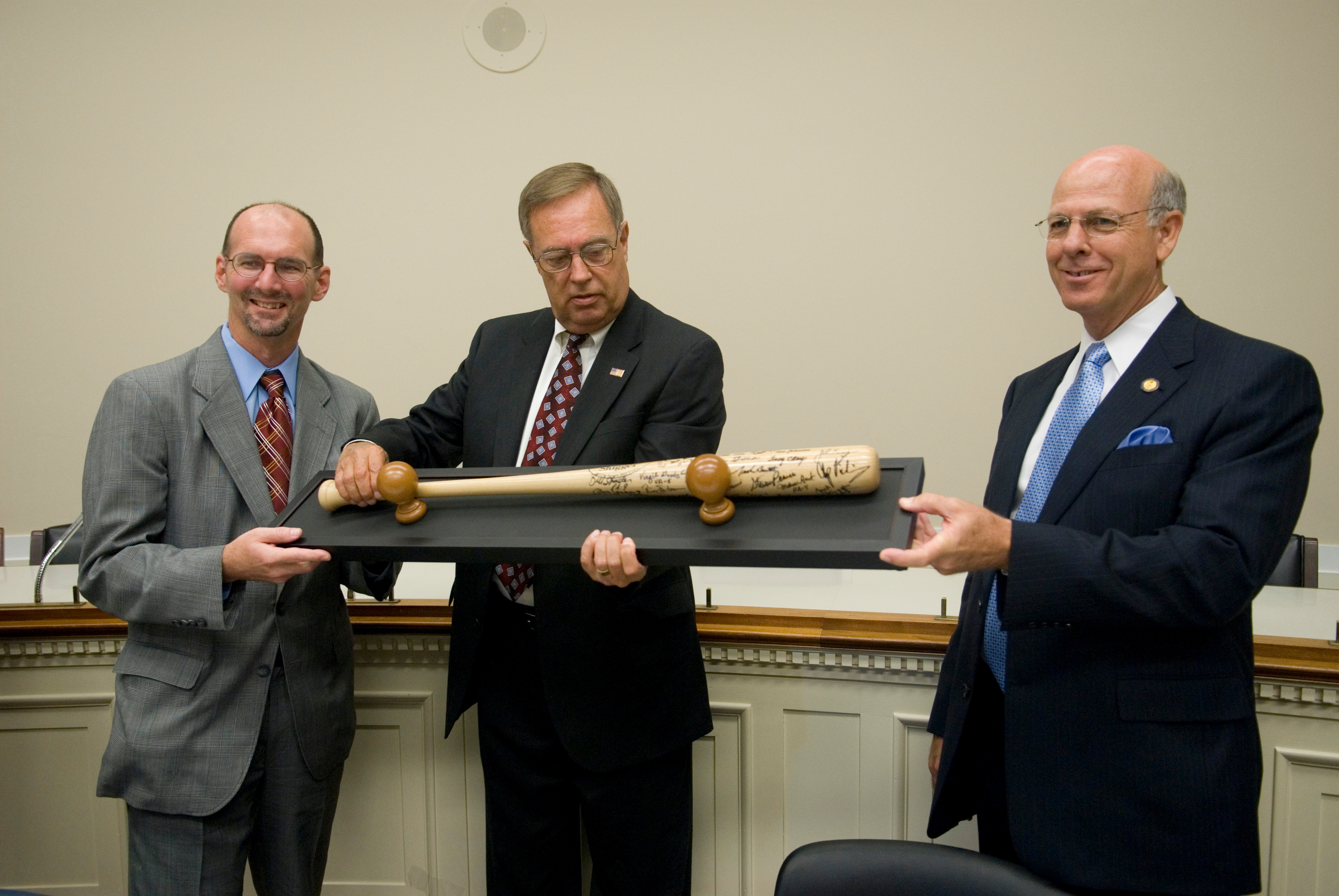 Rep. Mike Oxley, center, presents his legislative director, Tim Johnson, with a team-signed bat and a check as Rep. Steve Pearce, right, looks on in the Rayburn Building. The $5000 check, donated by Aramark fom their concession stand sales, was for the Multiple Myeloma Research Foundation.