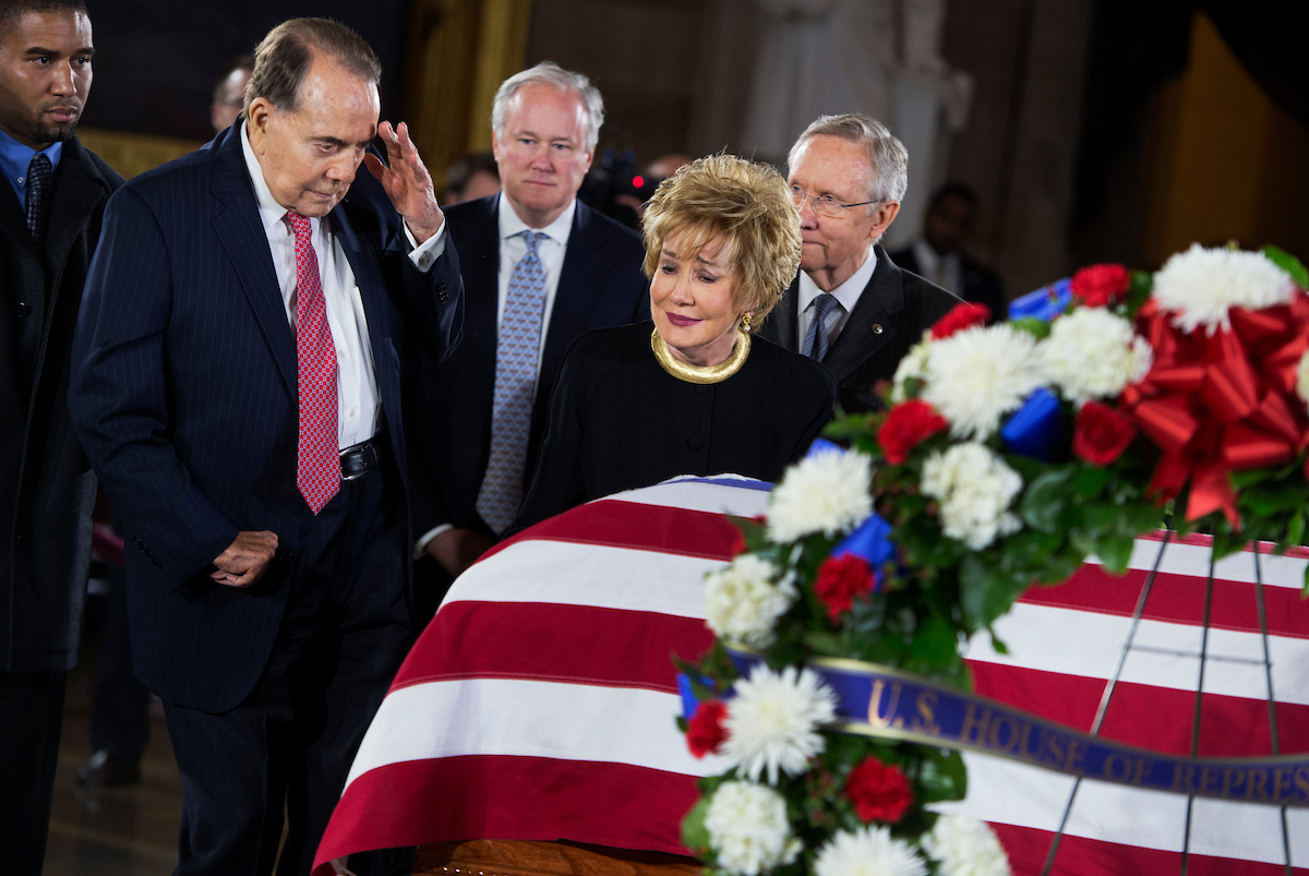 UNITED STATES - DECEMBER 20: Former Sen. Bob Dole, R-Kan., salutes the casket of the late Sen. Daniel Inouye, D-Hawaii, as his body lies in state in the Capitol rotunda, as Dole's wife, former Sen. Elizabeth Dole, R-N.C., looks on. Bob Dole and Inouye knew each other since they were recovering from World War II battle wounds. Dole was assisted to the casket saying