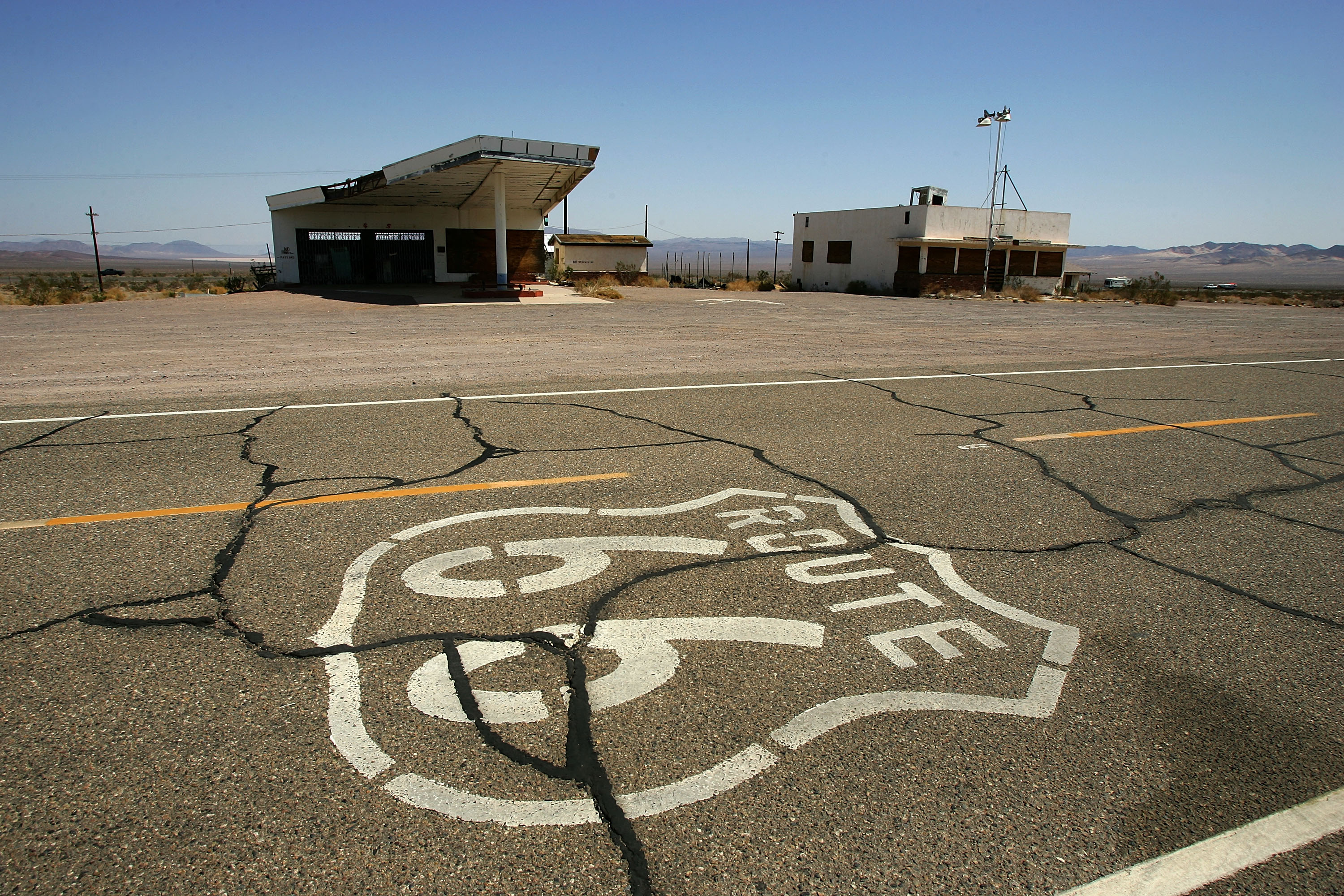 A symbol based on the original Route 66 road signs is seen painted on the highway near an abandoned gas station (L) and Cafe in Ludlow, California. (David McNew/Getty Images)