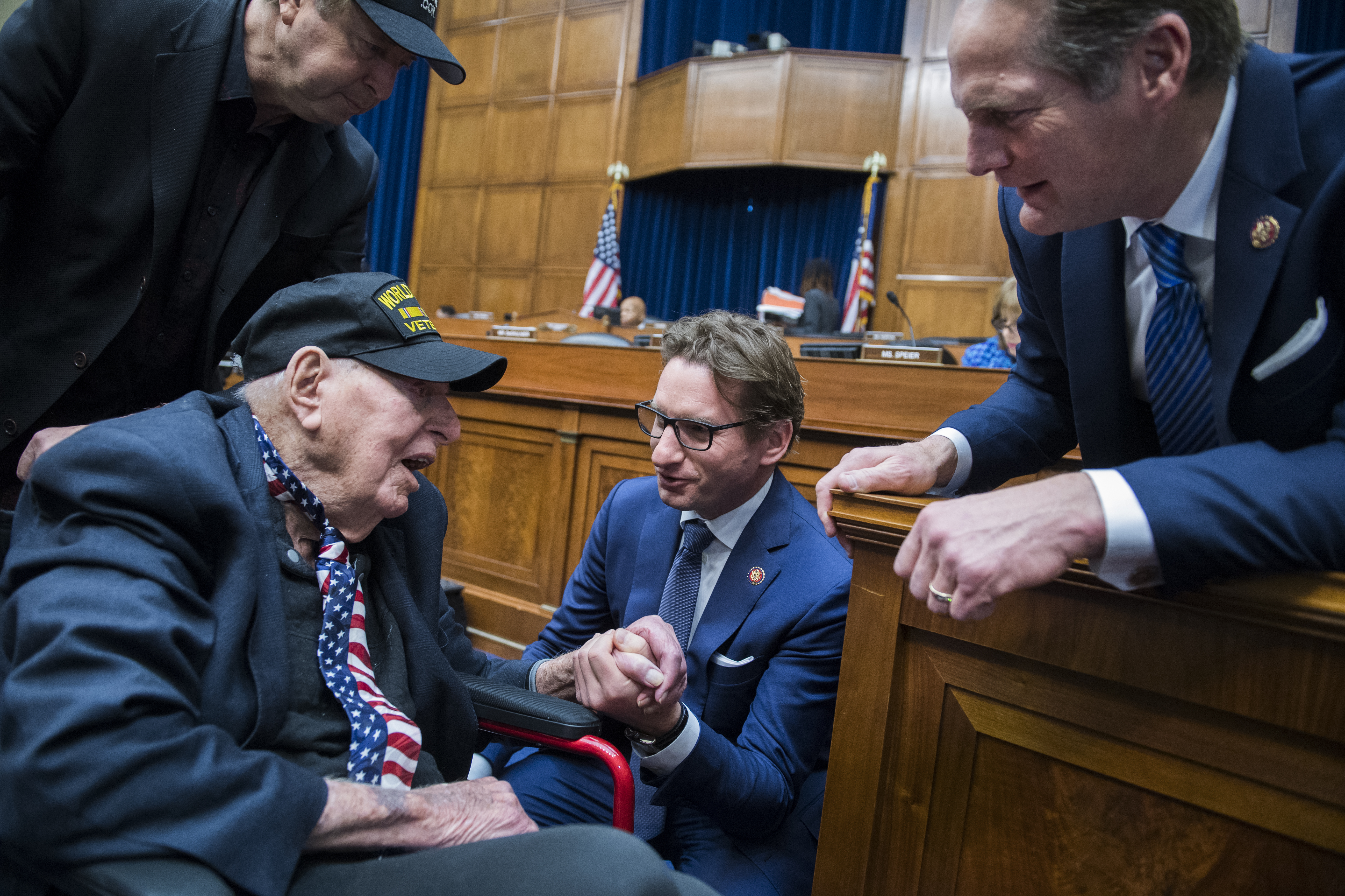 UNITED STATES - FEBRUARY 27: Reps. Dean Phillips, D-Minn., center, and Harley Rouda, D-Calif., right, talks with World War II veteran Sidney Walton, 100, of San Diego, during a break in a House Oversight and Reform Committee hearing in Rayburn Building featuring testimony by Michael Cohen, former attorney for President Donald Trump, on Russian interference in the 2016 election on Wednesday, February 27, 2019. Walton, seen with his son Paul, left, served in India during the war. (Photo By Tom Williams/CQ Roll Call)