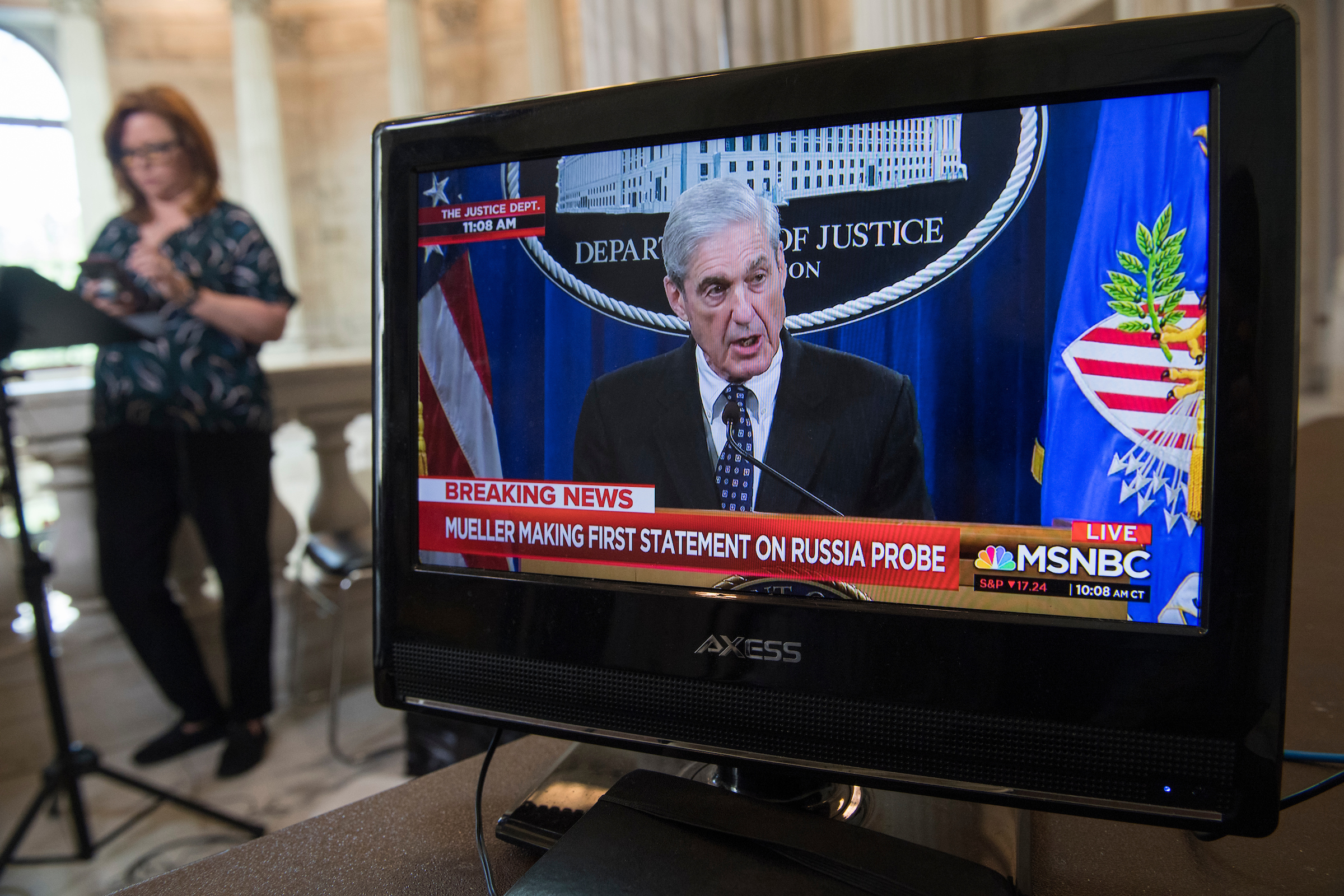 Special counsel Robert S. Mueller III is seen on a monitor in the Russell Building on Capitol Hill on Wednesday, making a statement at the Department of Justice on his investigation into Russian interference in the 2016 election. Kelly O'Donnell of NBC News listens in the background. (Tom Williams/CQ Roll Call)