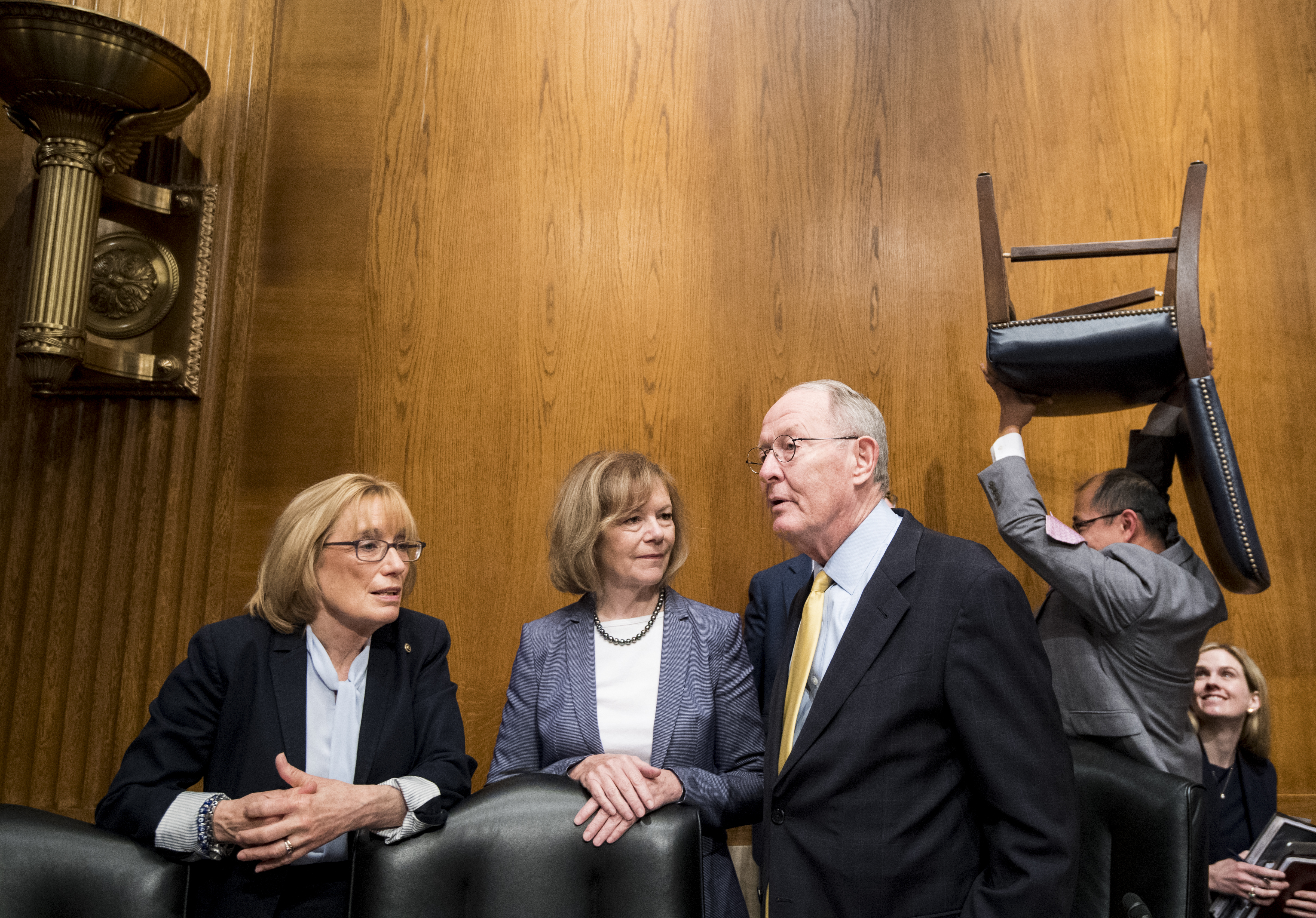 UNITED STATES - JUNE 18: From left, Sen. Maggie Hassan, D-N.H., Sen. Tina Smith, D-Minn., and chairman Sen. Lamar Alexander, R-Tenn., talk as a staffer carries a chair behind them before the start of the Senate Health, Education, Labor and Pensions Committee hearing on the 