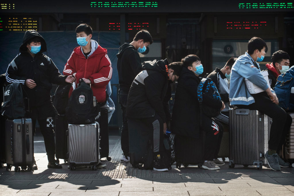 Chinese students wear masks as they wait to take a train in Beijing on Friday. The number of cases of a deadly new coronavirus rose to almost 9,700 in mainland China. (Kevin Frayer/Getty Images)